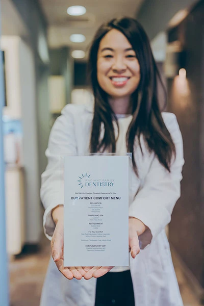 Dr. Christine Chan holding up a copy of Radiant Family Dentistry's patient comfort menu