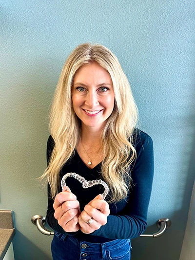 patient at Radiant Family Dentistry holding Invisalign aligners and smiling